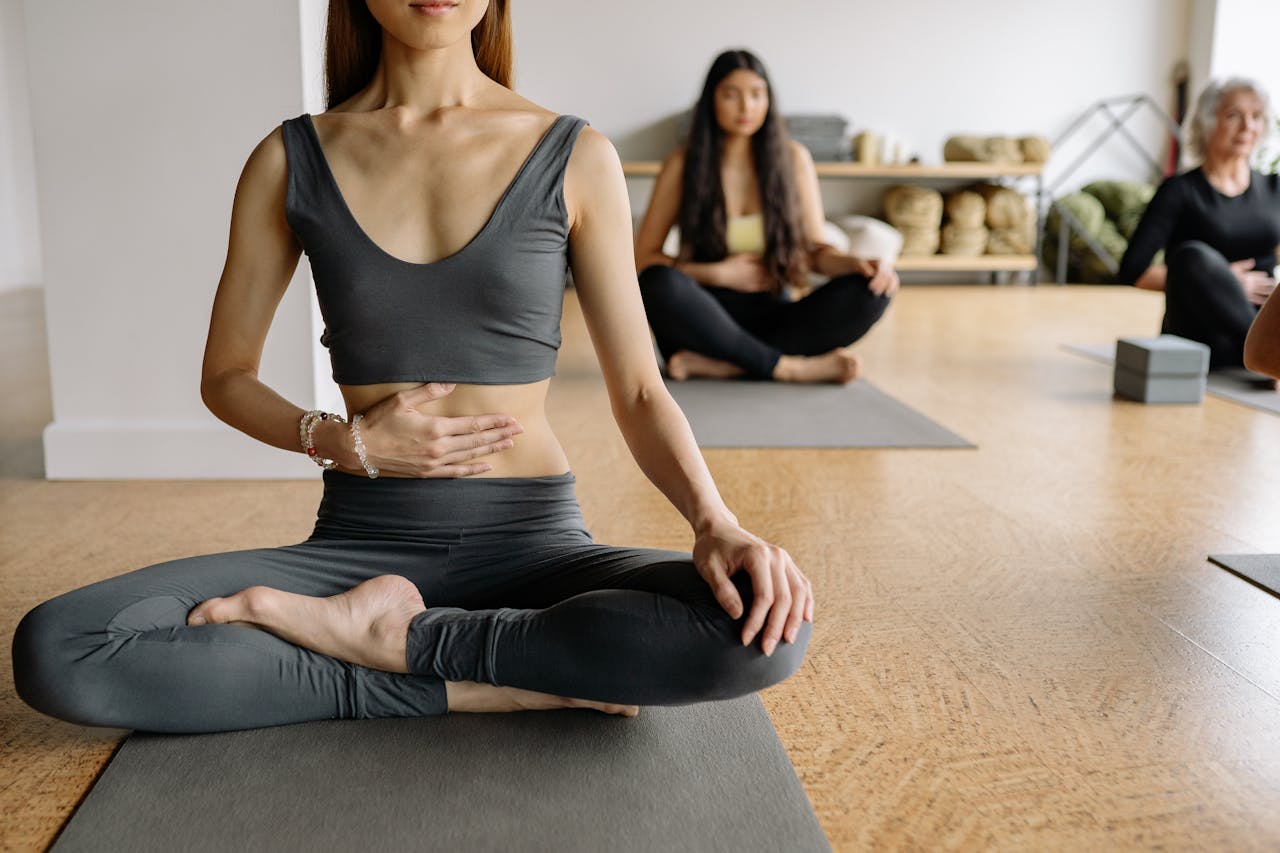 Women practicing yoga and meditation in a studio setting. Calm and focused atmosphere.
